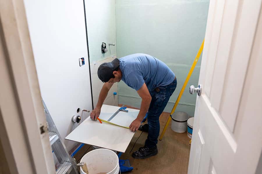 Tile installation expert installs large size bathroom tile.